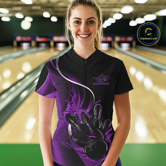 Female model front view inside bowling alley wearing black and purple quarter zip shirt with fiery bowling strike themed graphics
