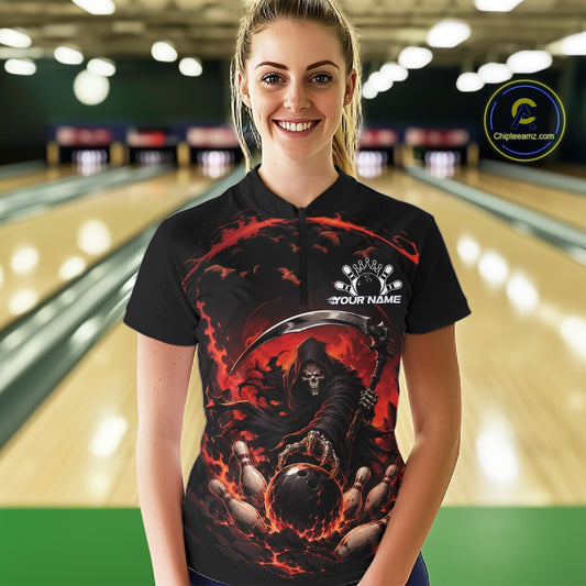 Front view of a female model wearing a black and red bowling quarter zip shirt showcasing a grim reaper reaching through swirling flames to command a blazing bowling ball striking scattered pins in a bowling lane.