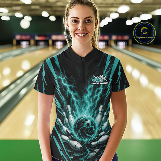 A woman stands in a bowling alley wearing a custom short-sleeve bowling quarter zip shirt bowling jersey with a black and teal graphic design of lightning and bowling pins.