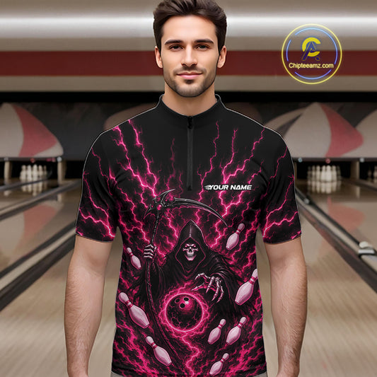 A man wearing a black short-sleeve quarter zip shirt with a vivid pink and purple lightning-bolt graphic and a grim reaper design, standing in a bowling alley.