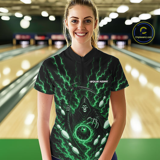 A woman stands in a bowling alley wearing a black short-sleeve bowling shirt with a green and black grim reaper graphic and the text 'YOUR NAME'