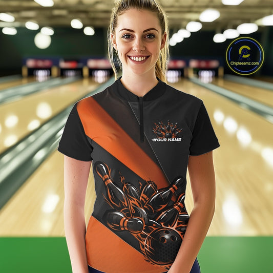 Female model front view at bowling lane wearing black and orange quarter zip shirt with fiery bowling ball knocking down pins illustration