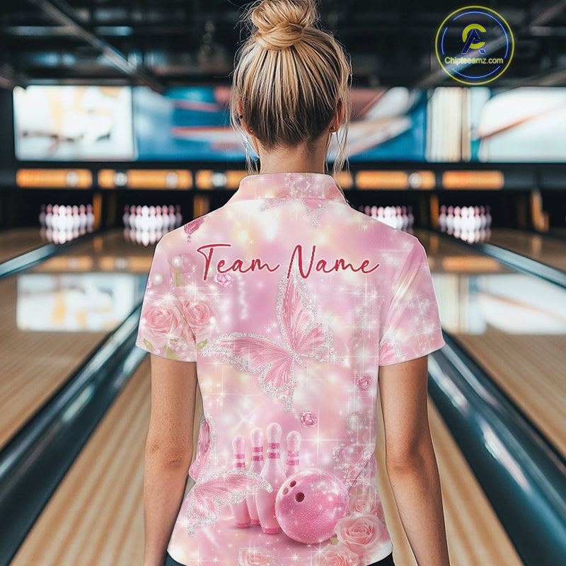 Back view of a female model in a bowling alley wearing a polo shirt showcasing pink glitter butterflies, diamonds, bowling pins, and bowling graphics.