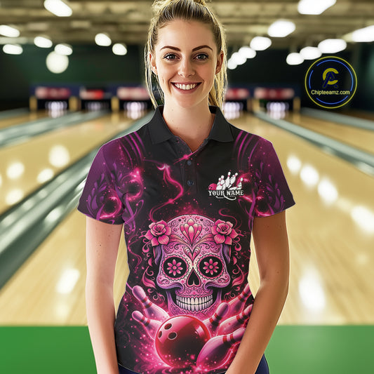 Female model at a bowling lane wearing a black and pink polo shirt with sugar skull artwork and vibrant bowling-themed design.