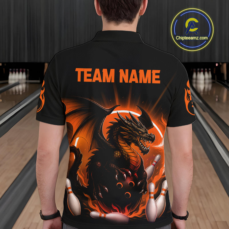 A person viewed from behind wearing a black short-sleeve bowling shirt with a large fiery dragon graphic and orange 'TEAM NAME' text on the back. Bowling lanes are visible in the background