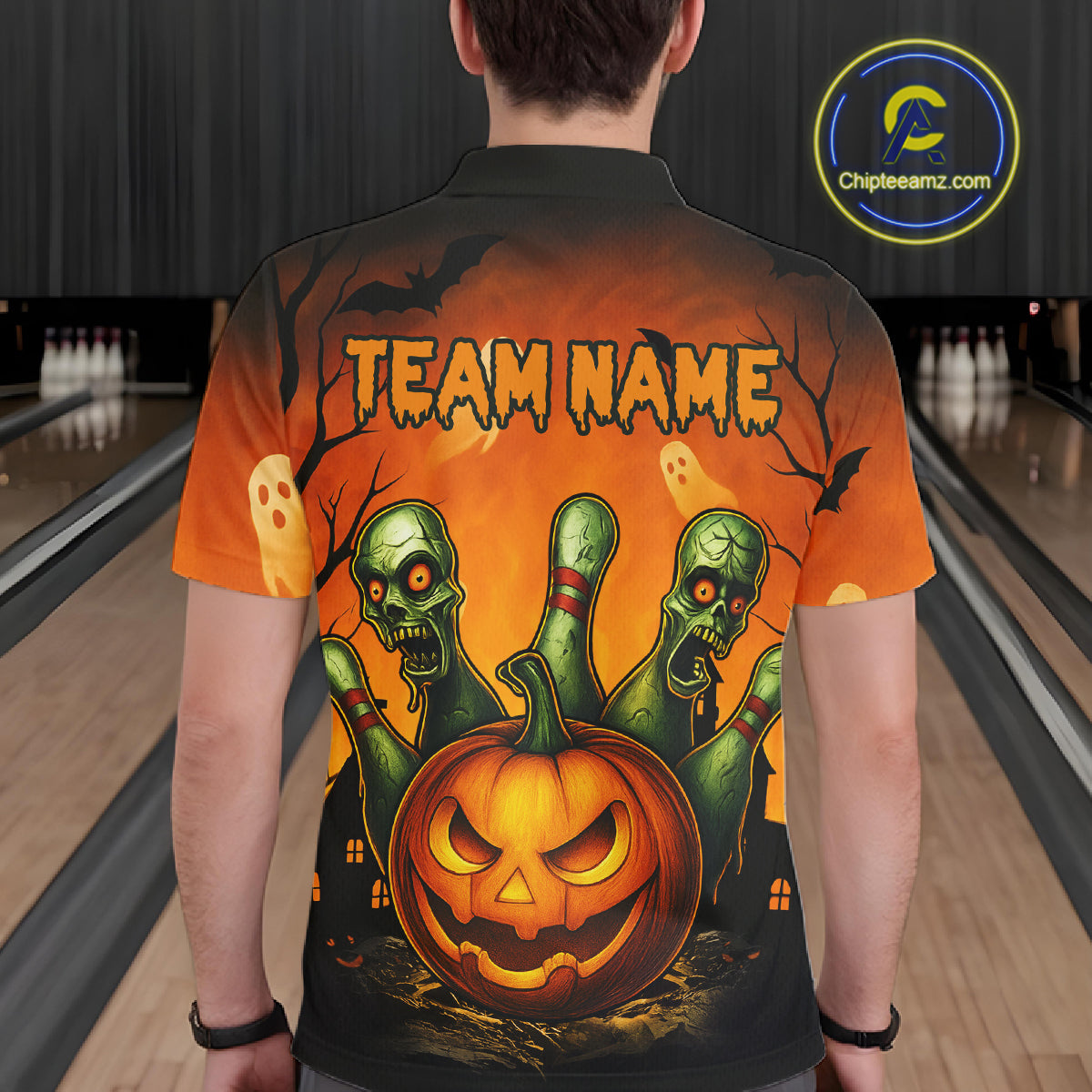 Person wearing a Halloween-themed shirt with a pumpkin and zombie design in a bowling alley.