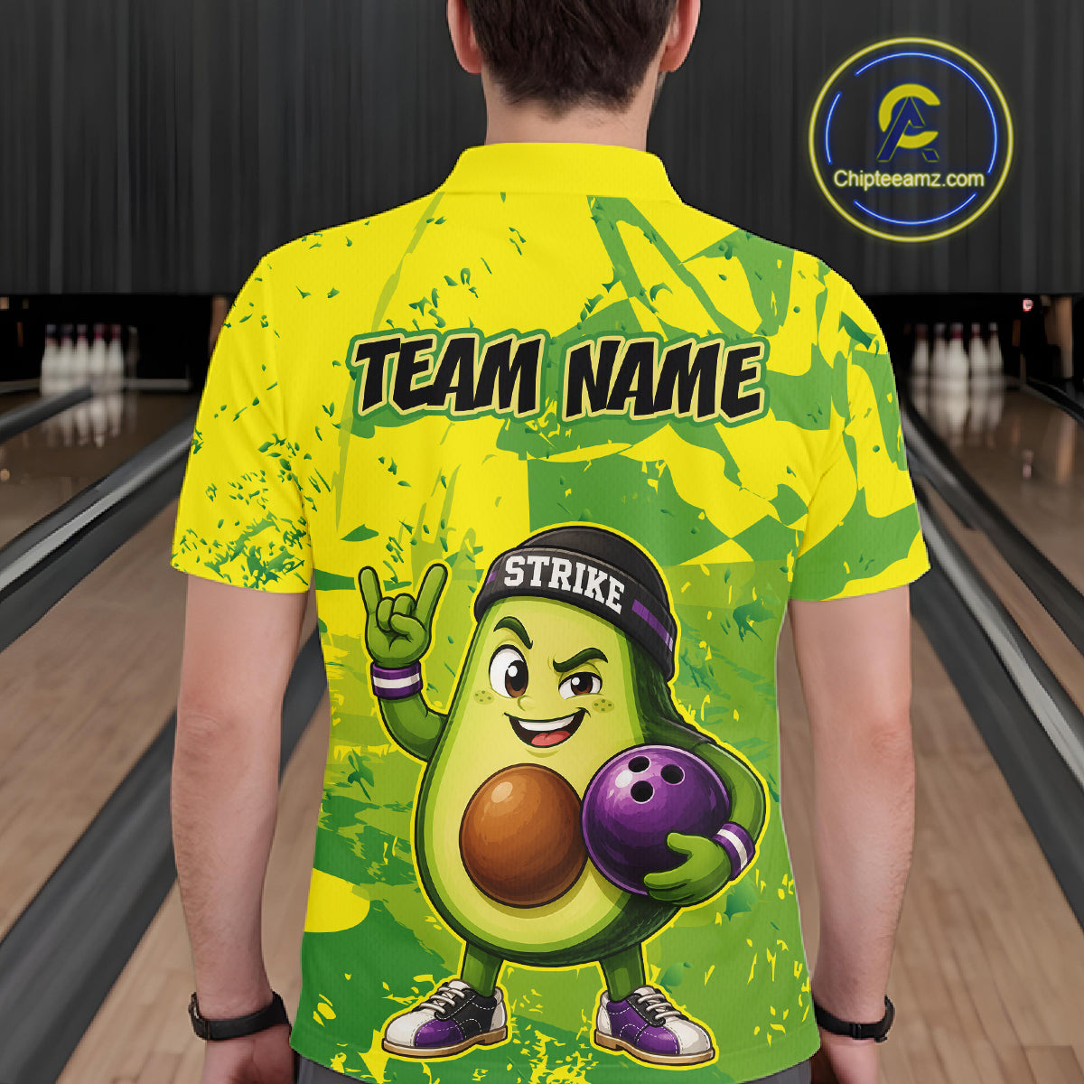 Person wearing a bright yellow and green bowling shirt with an avocado character holding a bowling ball on a bowling alley.