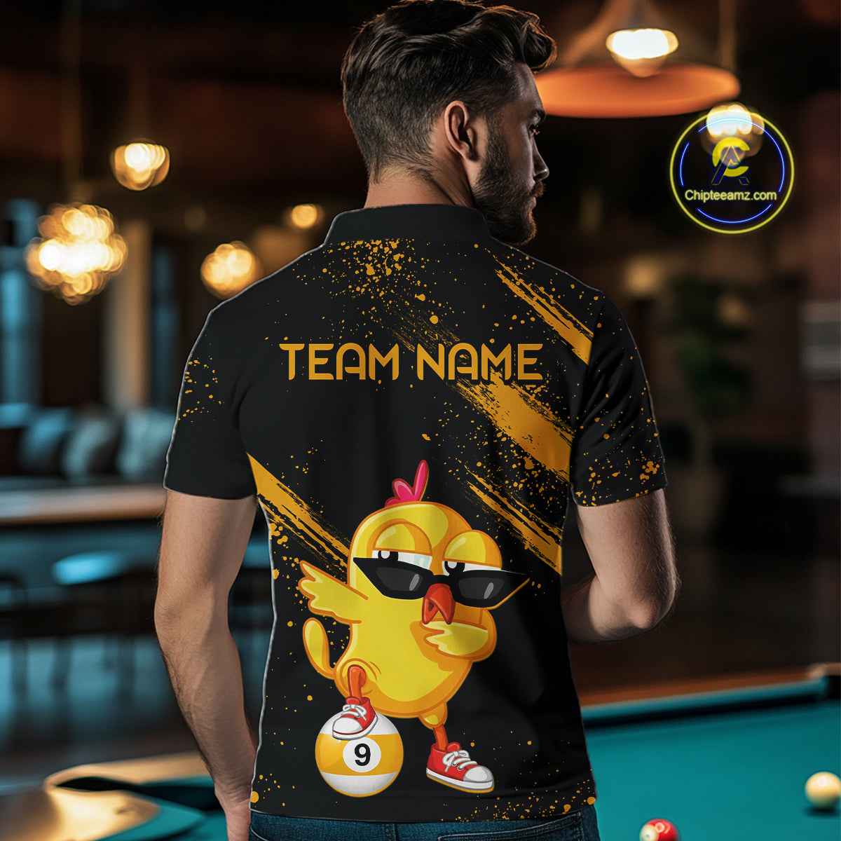 Person wearing a black and yellow shirt with a cartoon chicken design and 'Team Name' text, standing in a bar.