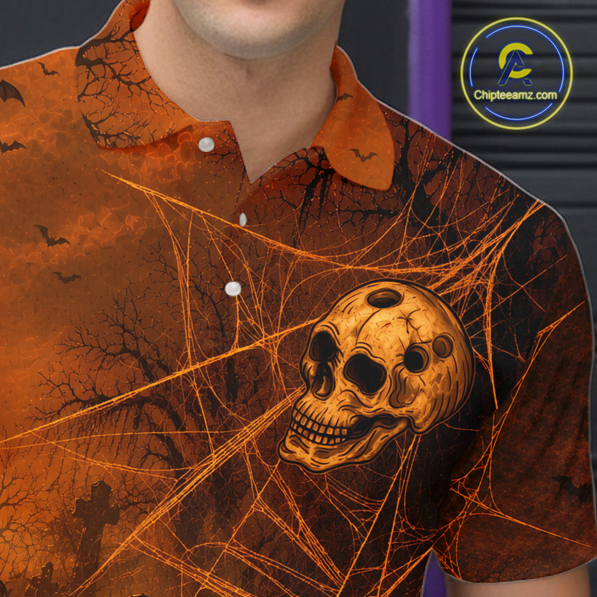 A close-up of a person wearing a short-sleeve button-up shirt with a Halloween-themed print. The shirt features an orange and black spiderweb design with a large skull graphic on the front.