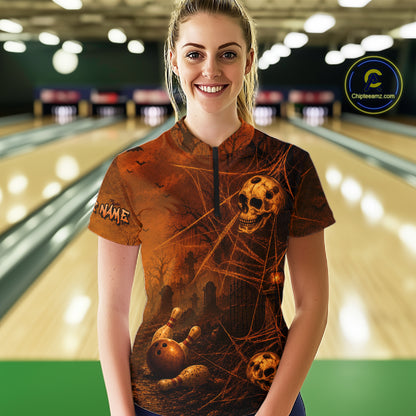 A woman standing in a bowling alley wearing a short-sleeve collared bowling shirt with a dark brown and black Halloween-themed graphic print featuring skulls, bones, and cobwebs. The shirt has a mock neck and a black zipper.