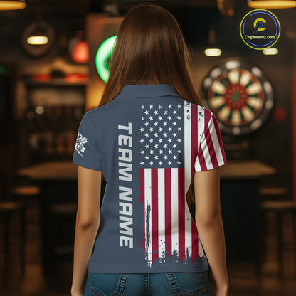 A woman viewed from behind wearing a short-sleeve polo shirt with a distressed American flag print on the back and the words 'TEAM NAME' printed vertically. The shirt is navy blue with red, white, and blue graphics.