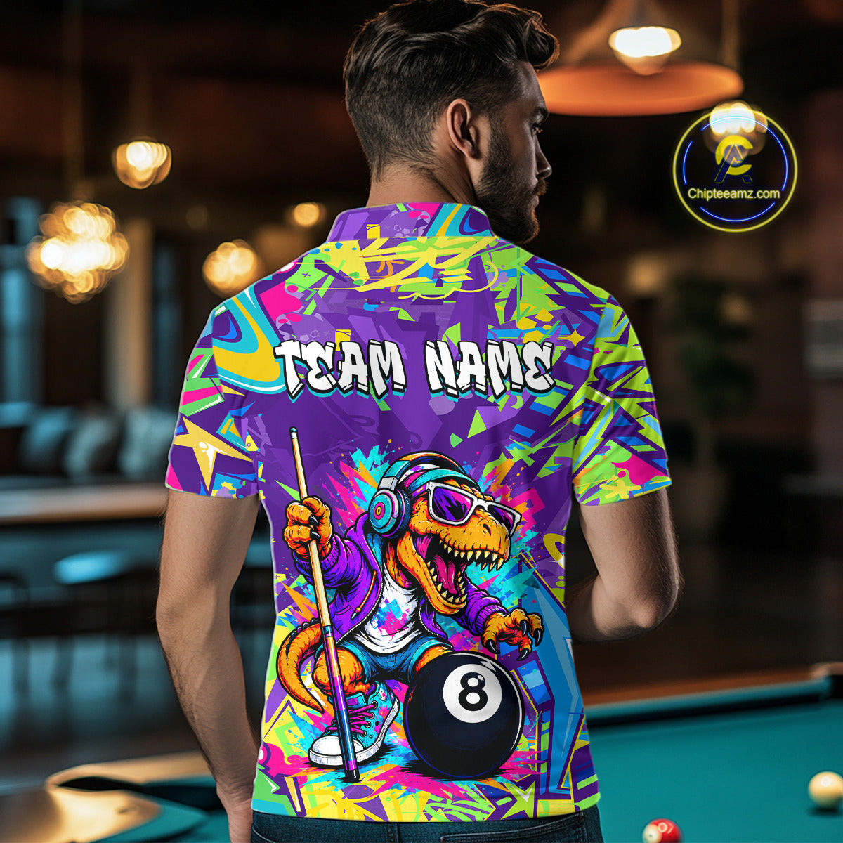 Person wearing a colorful shirt with a dinosaur and pool ball design in a bar setting.