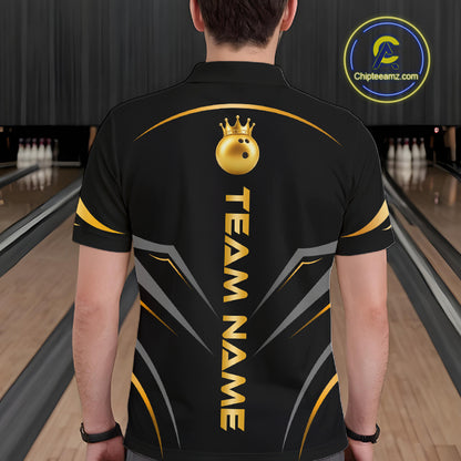 A person viewed from behind wearing a black bowling shirt with gold and gray graphic details, including a crown icon and the text 'TEAM NAME'. The background shows bowling lanes in a blurred indoor bowling alley.