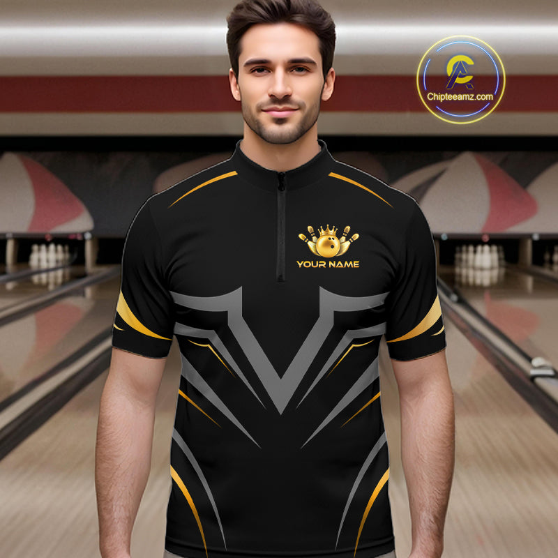 A man wearing a black short-sleeve bowling jersey with gold and gray graphic patterns, standing in a bowling alley. The jersey features a gold crown and trophy graphic with the text 'YOUR NAME' on the chest.