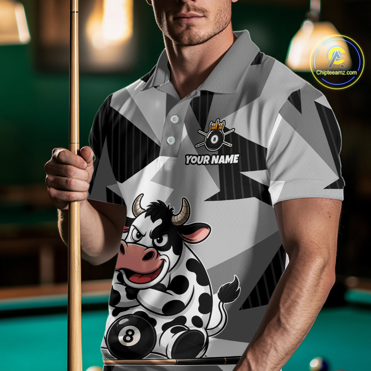 Person wearing a polo shirt with a cow design and pool cue, standing in front of a pool table.