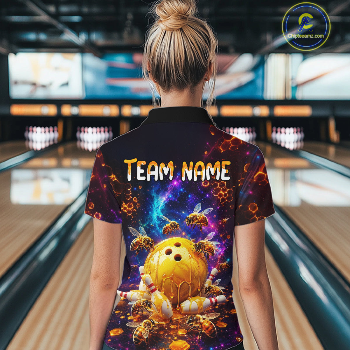 Woman wearing of a dark bowling quarter zip with cosmic honeycomb graphics, bees, honey-dripping bowling balls, pins, and custom team name text.