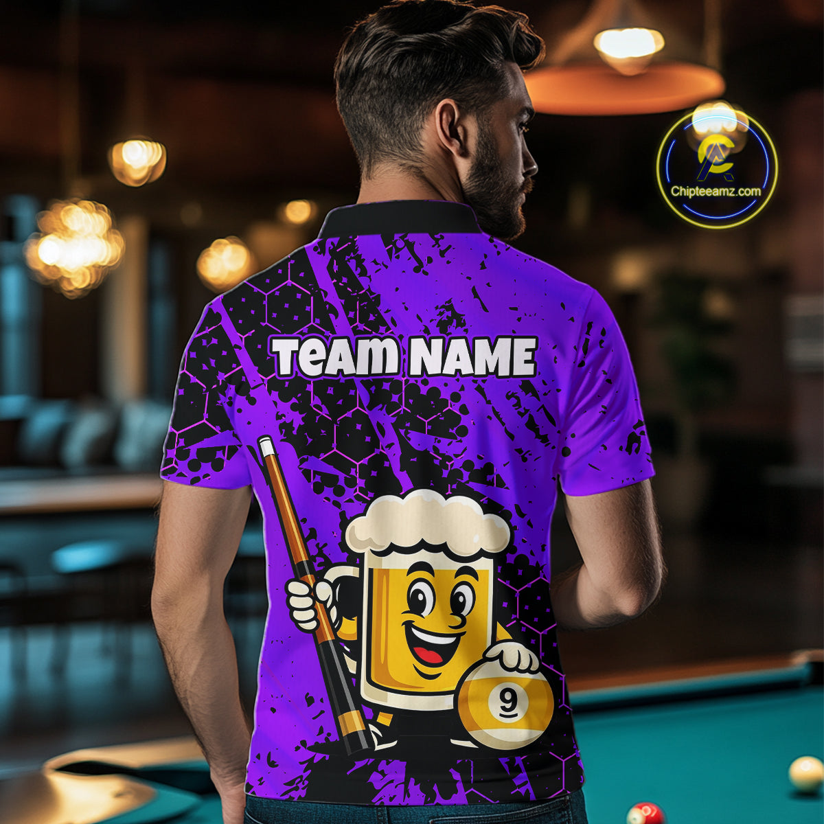 Man wearing a blue funny beer with a cartoon beer mug and pool cue design, standing in a bar.