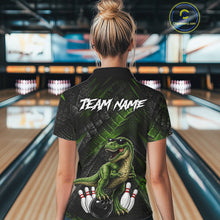 Load image into Gallery viewer, Women wearing bowling quarter zip shirt featuring a dinosaur standing among bowling pins and ball artwork on black green textured background.