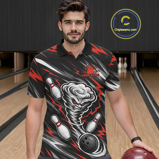 A man wearing a black short-sleeve bowling-themed polo shirt with a red and gray tornado graphic, bowling pins, and lightning bolts, standing in a bowling alley holding a bowling ball. 