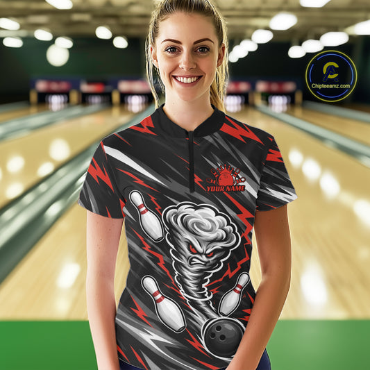 A woman wearing a custom bowling-themed short-sleeve quarter zip shirt with a black, gray, and red lightning bolt pattern and a cartoon tornado graphic, standing in a bowling alley. 
