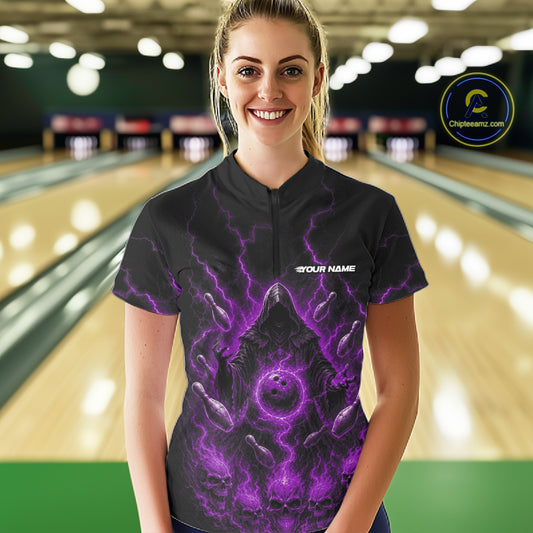 A woman wearing a black bowling shirt with a purple cosmic horror design, standing in front of a blurred bowling alley background. 