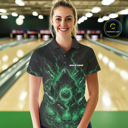 A woman stands in a bowling alley wearing a black short-sleeve polo shirt with a glowing green grim reaper graphic and the text 'YOUR NAME'. 