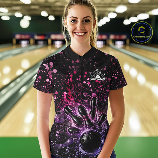 Female model wearing a black bowling quarter-zip shirt at the lane with flaming bowling artwork and pink-purple music-themed splatter accents.