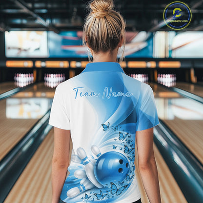Back view of a women s white and blue bowling polo shirt displaying butterfly accents and bowling-themed graphics in a bowling venue.