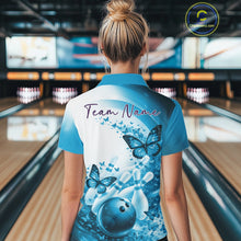 Load image into Gallery viewer, Female model in a blue bowling polo with butterfly artwork and bowling graphics, back view inside a bowling alley