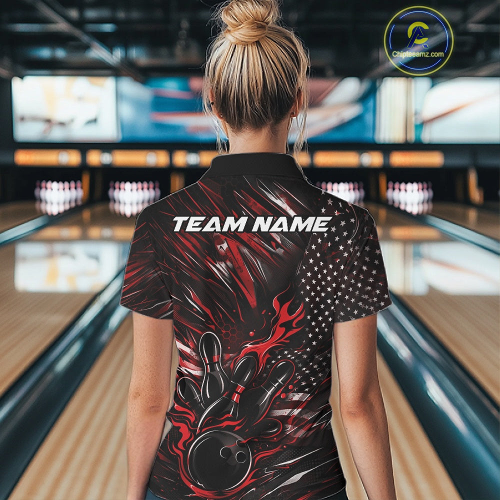 Back view of a female model in a bowling venue wearing a black and red polo shirt featuring a flaming bowling ball hitting the pins with flag-inspired graphics.