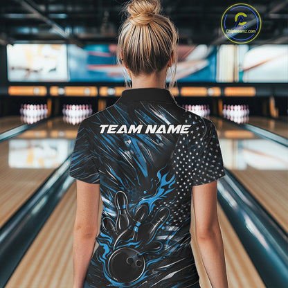 Female model at a bowling lane, back view of black and blue quarter zip shirt showcasing patriotic flames bowling ball striking pins with American flag styling