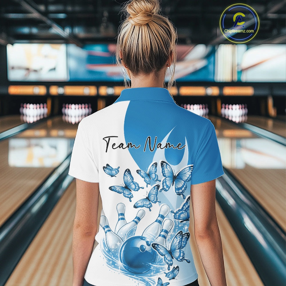 Back view of a female model in a white and blue bowling polo with butterfly graphics and bowling artwork at the bowling lane