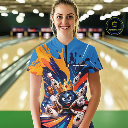 Front view of a female model wearing a bowling quarter zip shirt featuring a crowned cartoon bowling ball holding a royal scepter with cheering animated bowling pins and colorful paint splashes in a bowling lane.