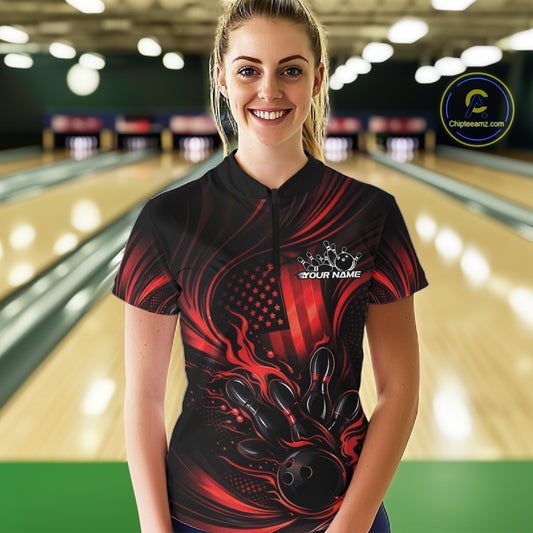 Female model at a bowling lane wearing a black and red bowling quarter-zip shirt with patriotic bowling strike graphics and flag-inspired accents.
