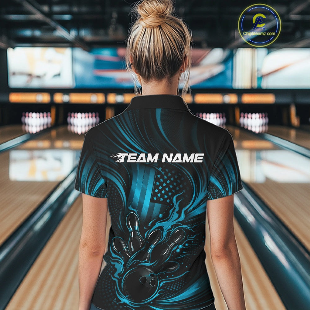 Back view of a female model in a bowling alley wearing a black and turquoise blue polo showcasing a flaming bowling ball striking pins.