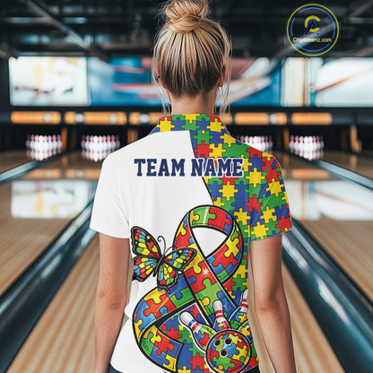 Female model at a bowling lane, back view of white polo shirt showing autism ribbon puzzle design, butterfly accents, and bowling strike illustration
