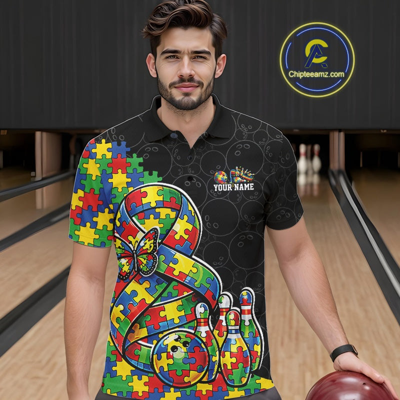 Male model in a bowling lane wearing a black polo shirt, front view featuring autism ribbon puzzle design, butterfly, and bowling strike artwork