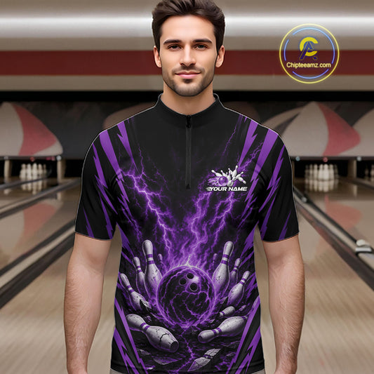 A man wearing a black short-sleeve bowling quarter zip shirt with a purple lightning-bolt and bowling pins graphic, standing in a bowling alley.