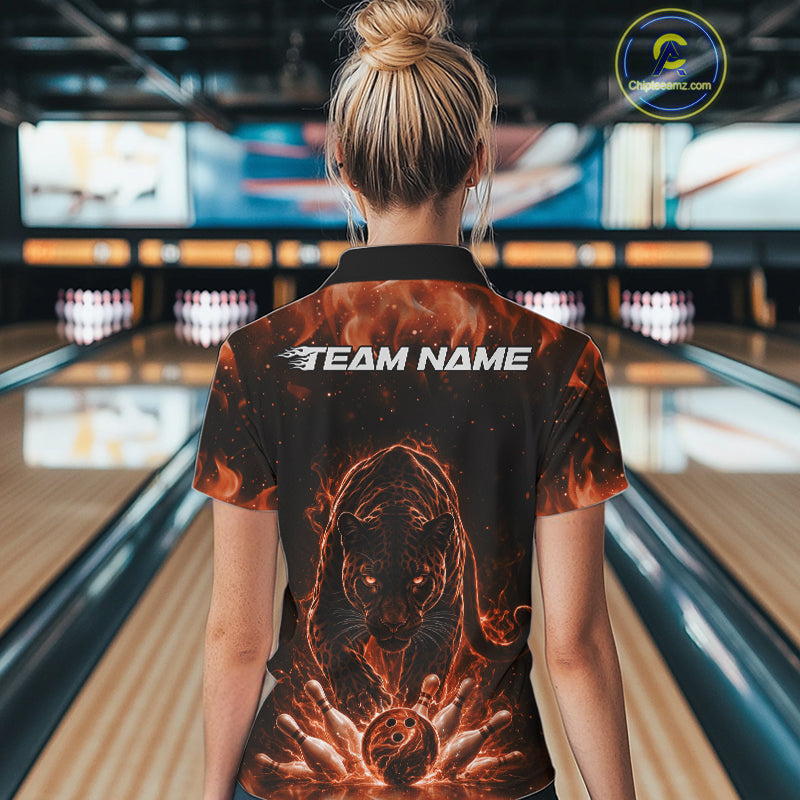 Back view of a female model in a bowling lane wearing a black polo shirt with glowing orange electric panther design and bowling ball crashing through pins artwork.