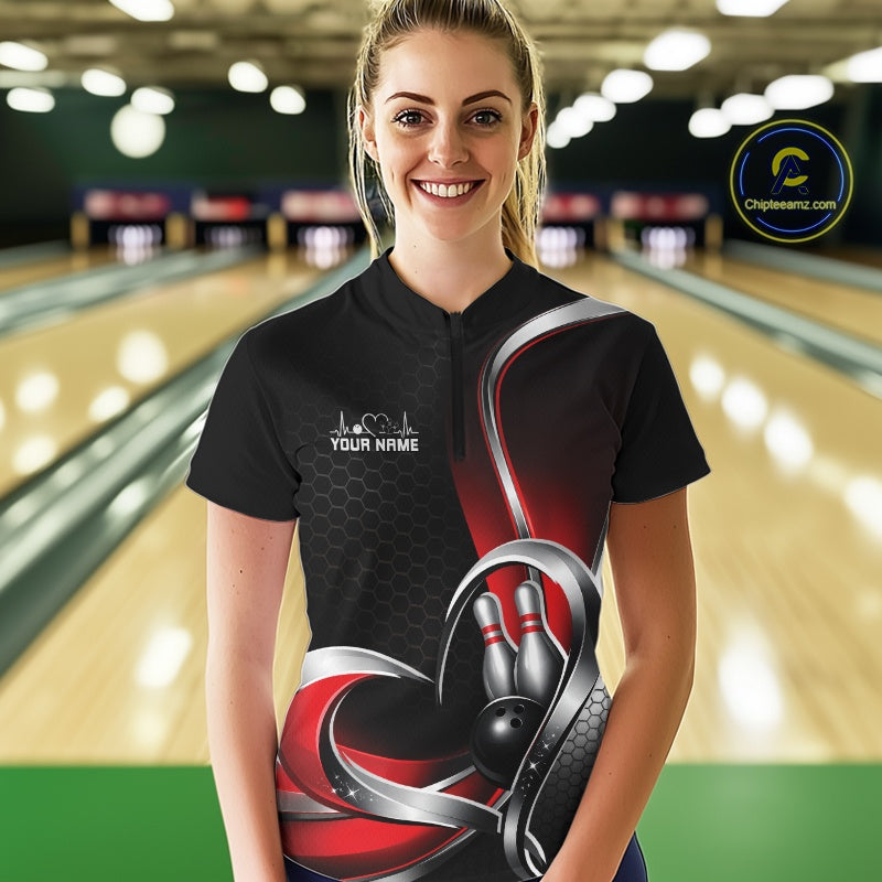 Female model at a bowling lane wearing a black and red quarter zip shirt, showing honeycomb graphics with a heart framing a bowling ball hitting pins.