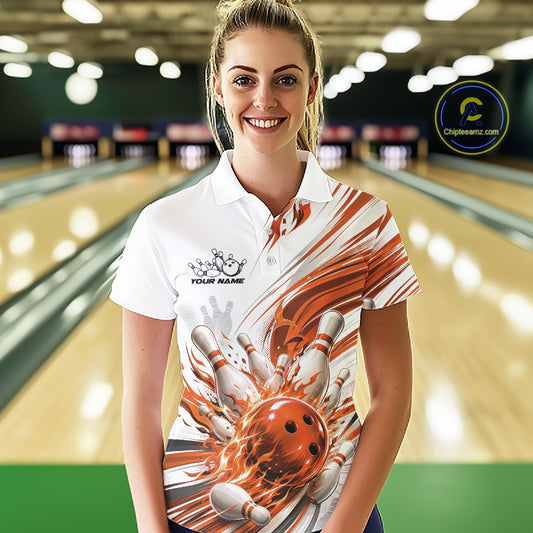 A woman stands in a bowling alley wearing a custom printed white short-sleeve polo shirt with a graphic of a flaming orange bowling ball striking pins. The shirt features a custom logo on the left chest