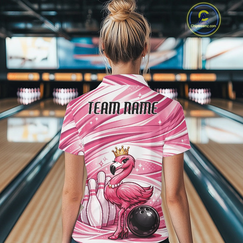 Back view of a female model in a bowling alley wearing a pink polo shirt featuring a crowned flamingo beside bowling pins and a bowling ball.