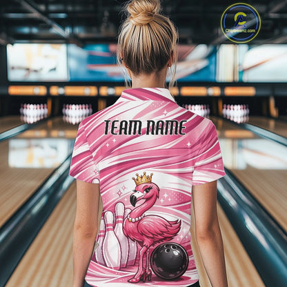 Back view of a female model in a bowling alley wearing a pink polo shirt featuring a crowned flamingo beside bowling pins and a bowling ball.