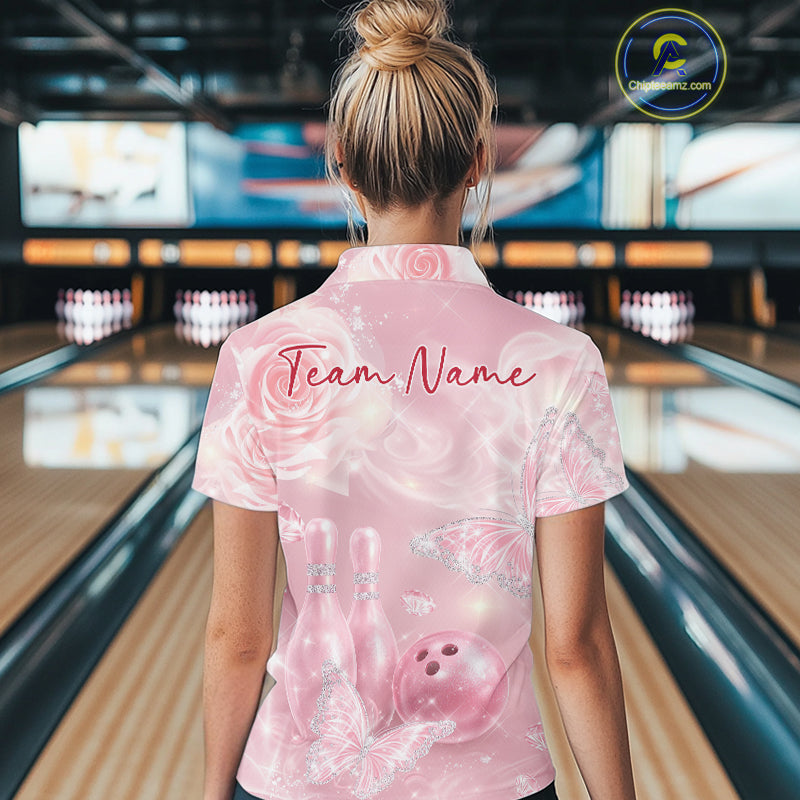 Female model shown from the back in a bowling venue wearing a quarter-zip shirt with pink glitter butterflies, roses, bowling pins, and bowling ball accents.