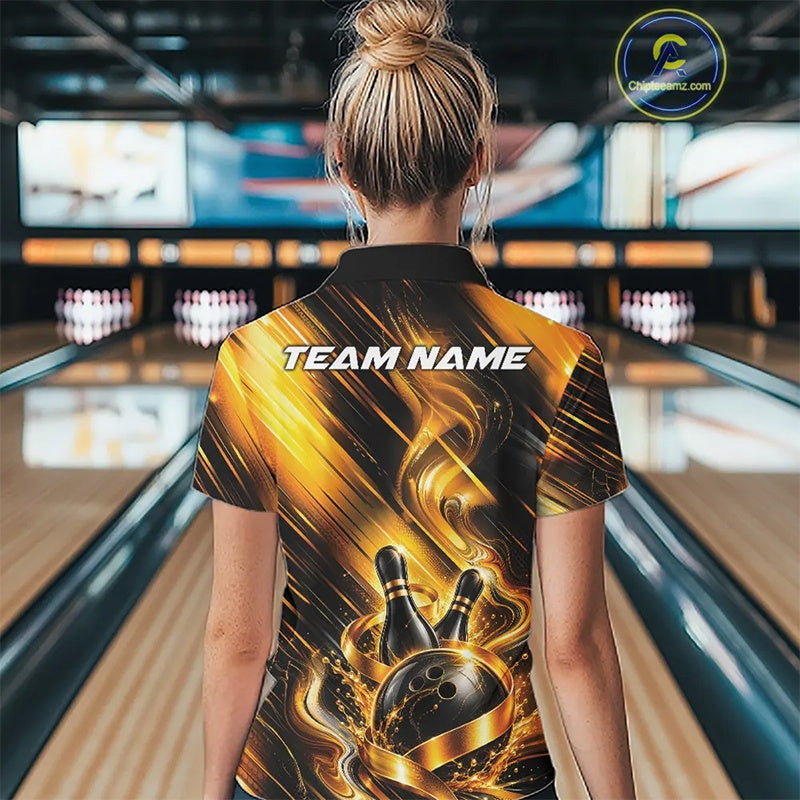 Back view of a female model wearing a bowling quarter zip shirt featuring a black and gold bowling ball hitting the pins graphic with flowing metallic ribbon accents at a bowling lane.