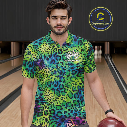 A man stands in a bowling alley wearing a yellow, brown, and black leopard-print bowling shirt with a bowling pin graphic and “Your Name” on the chest.