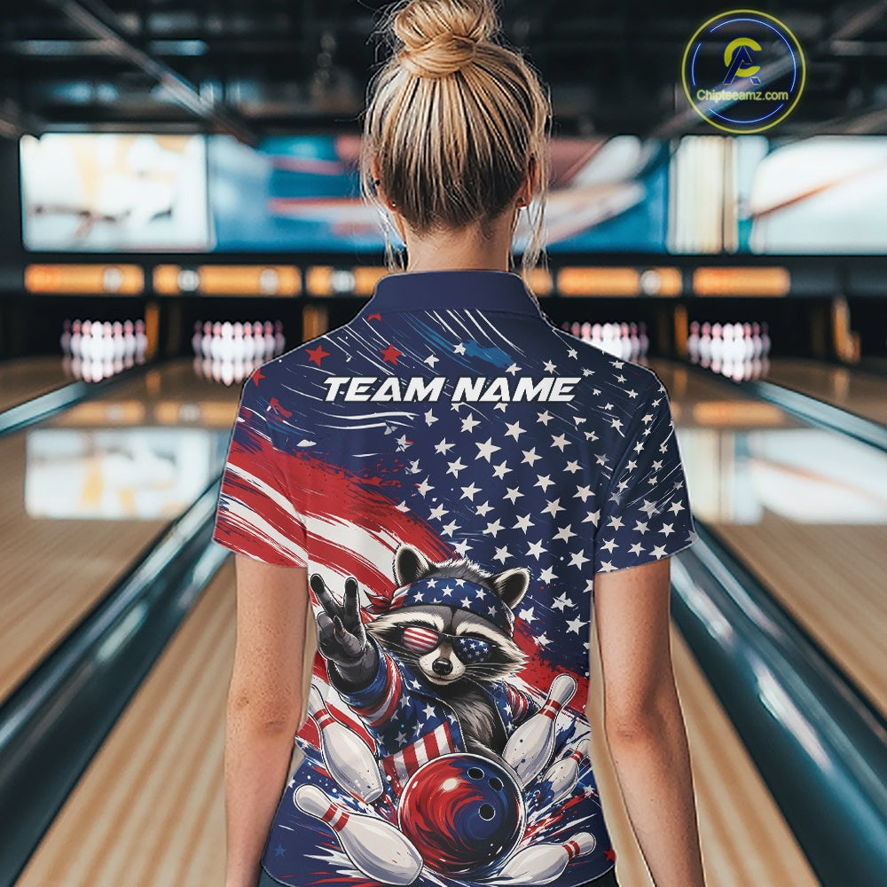 Back view of a female model wearing a bowling quarter zip shirt featuring a patriotic raccoon flashing a peace sign with a red, white, and blue bowling ball crashing through pins beneath a flowing American flag in a bowling lane.