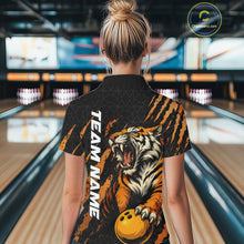 Load image into Gallery viewer, Back view of a female model wearing a black and yellow bowling quarter-zip shirt in a bowling lane, featuring a roaring tiger holding a yellow bowling ball with orange claw-stripe graphics and a geometric background pattern.