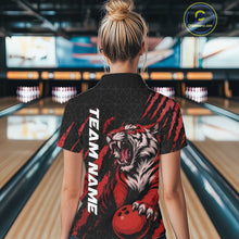 Load image into Gallery viewer, Back view of a female model wearing a black and red bowling polo shirt in a bowling lane, featuring a roaring tiger holding a red bowling ball with matching red claw-stripe artwork and a geometric background pattern.