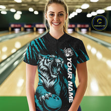 Load image into Gallery viewer, Front view of a female model at a bowling lane wearing a black and teal blue bowling quarter-zip shirt showcasing a roaring tiger holding a teal blue bowling ball with teal blue claw-stripe artwork and a geometric background pattern.